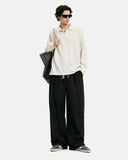 Full body shot of cream polo shirt paired with black drawstring waist pants
