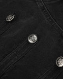 metal button strap detail on black denim jacket close-up